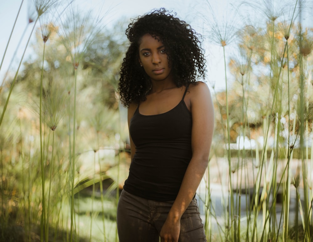 Femme portant un haut à bretelles spaghetti noires debout près des plantes