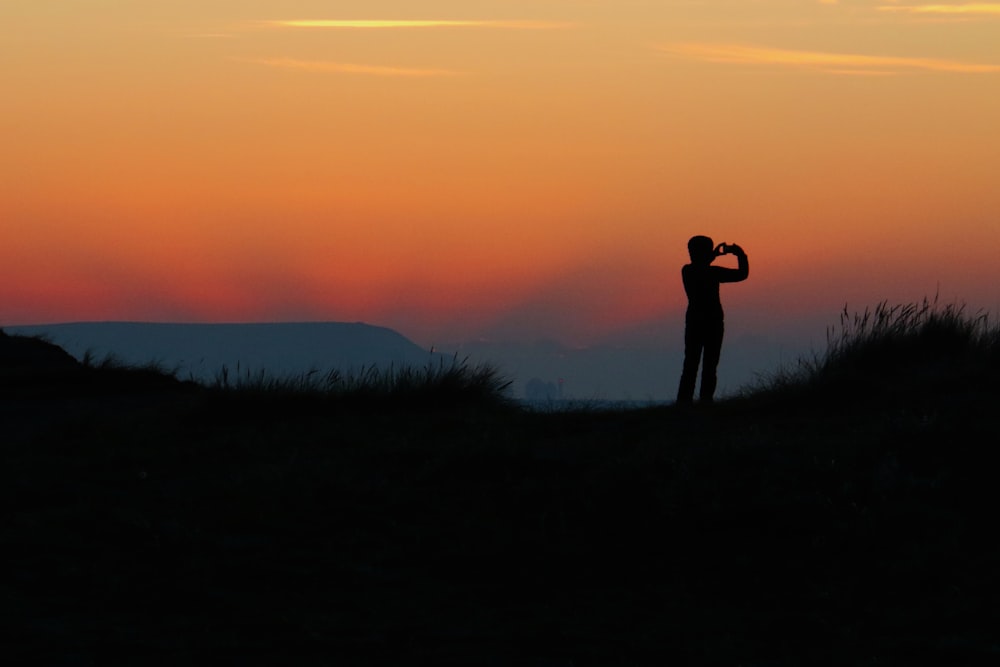 silhouette d’une personne prenant une photo au coucher du soleil