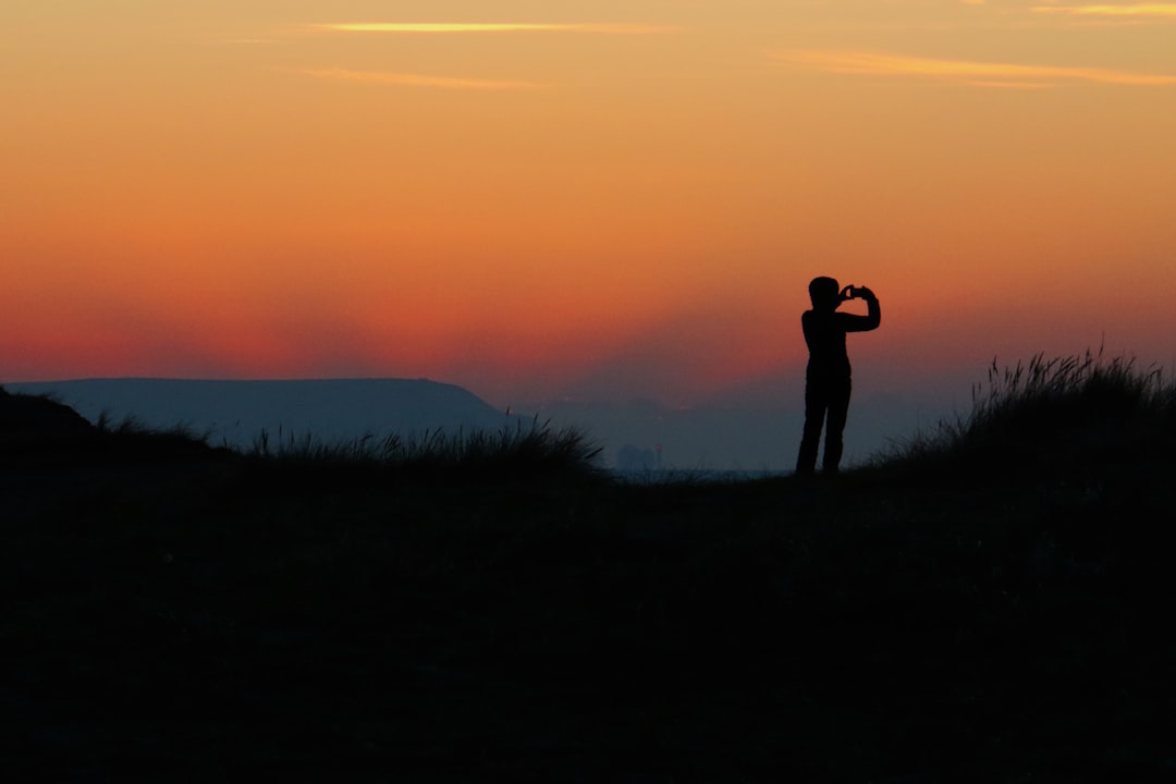 silhouette of person taking photo during sundown