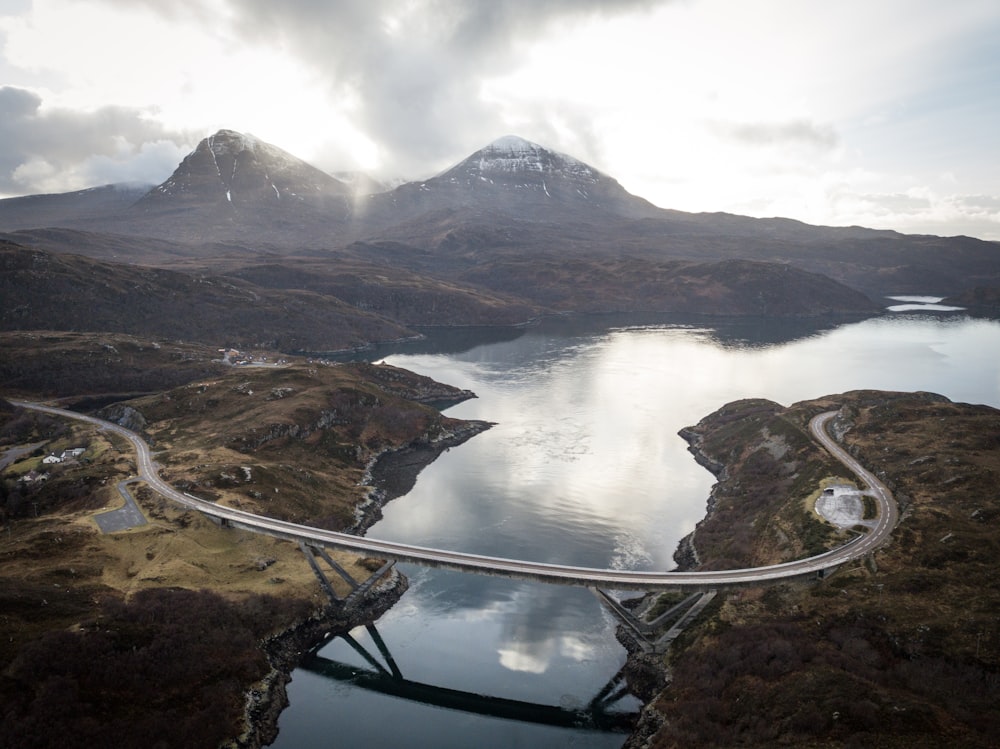 concrete road bridge near two snow-capped mountains during daytime