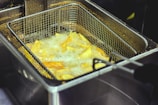 Close-up of a shiny electric fryer bubbling with golden fries.