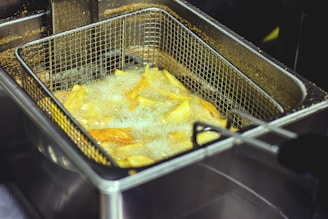 Industrial stainless steel fryer filled with golden fried food.