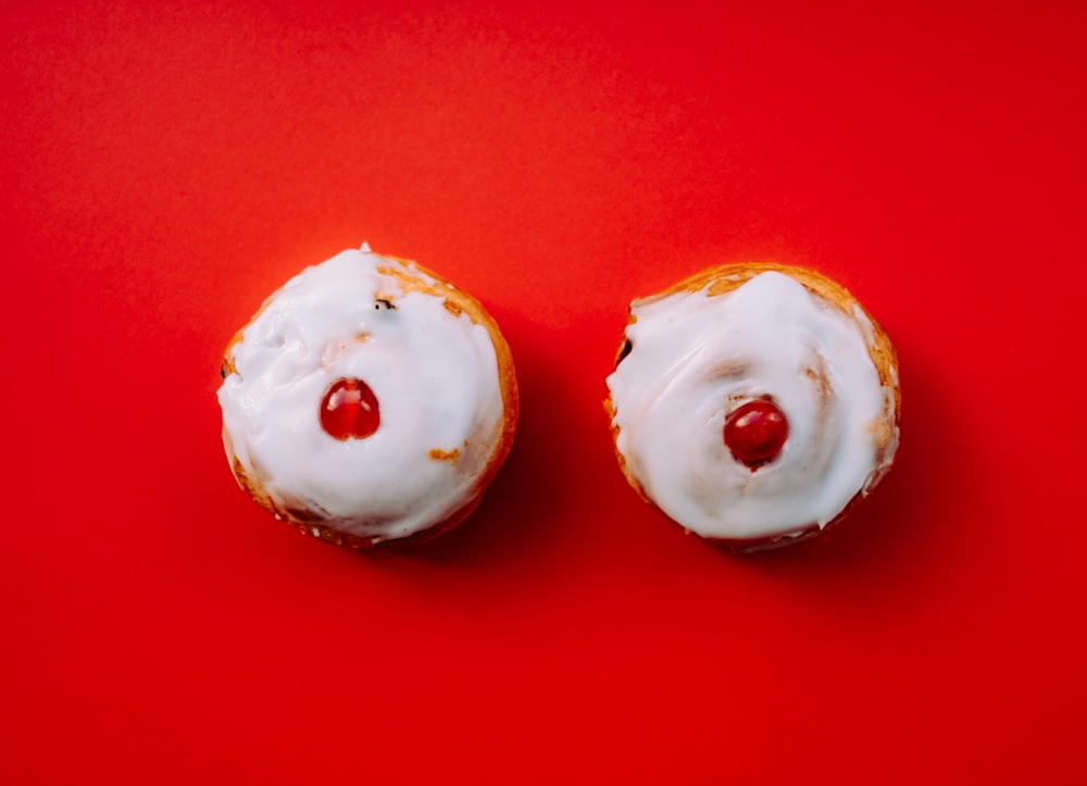 Dos cupcakes blancos glaseados con coberturas de cereza