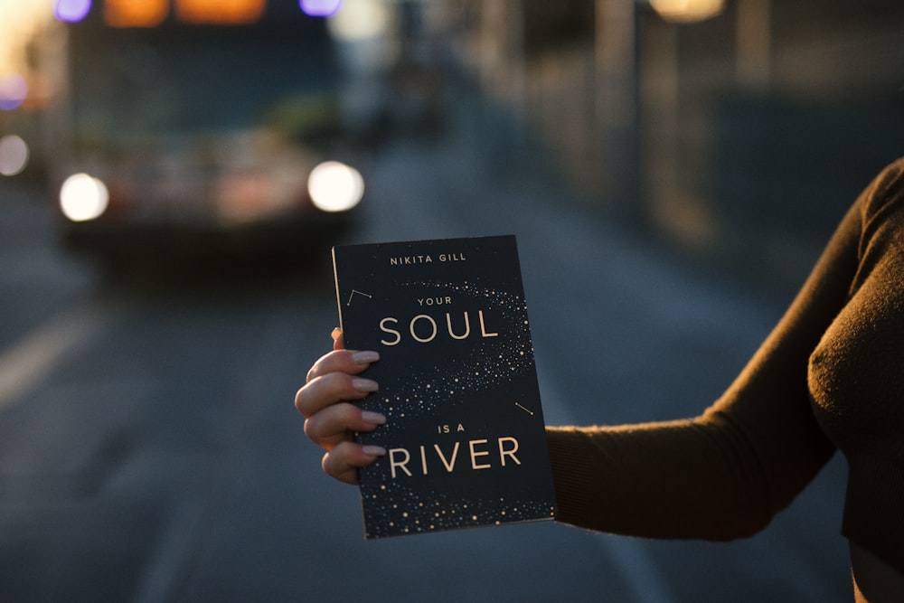 person holding Your Soul is a River book