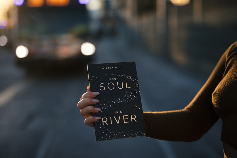 Person, die das Buch "Your Soul is a River" in der Hand hält