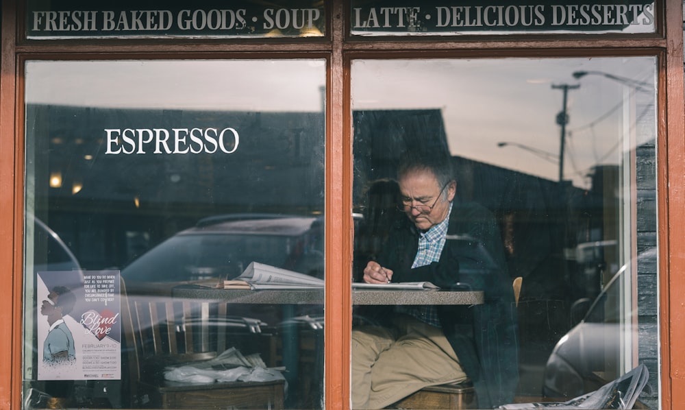 man sitting on chair while writing on pape