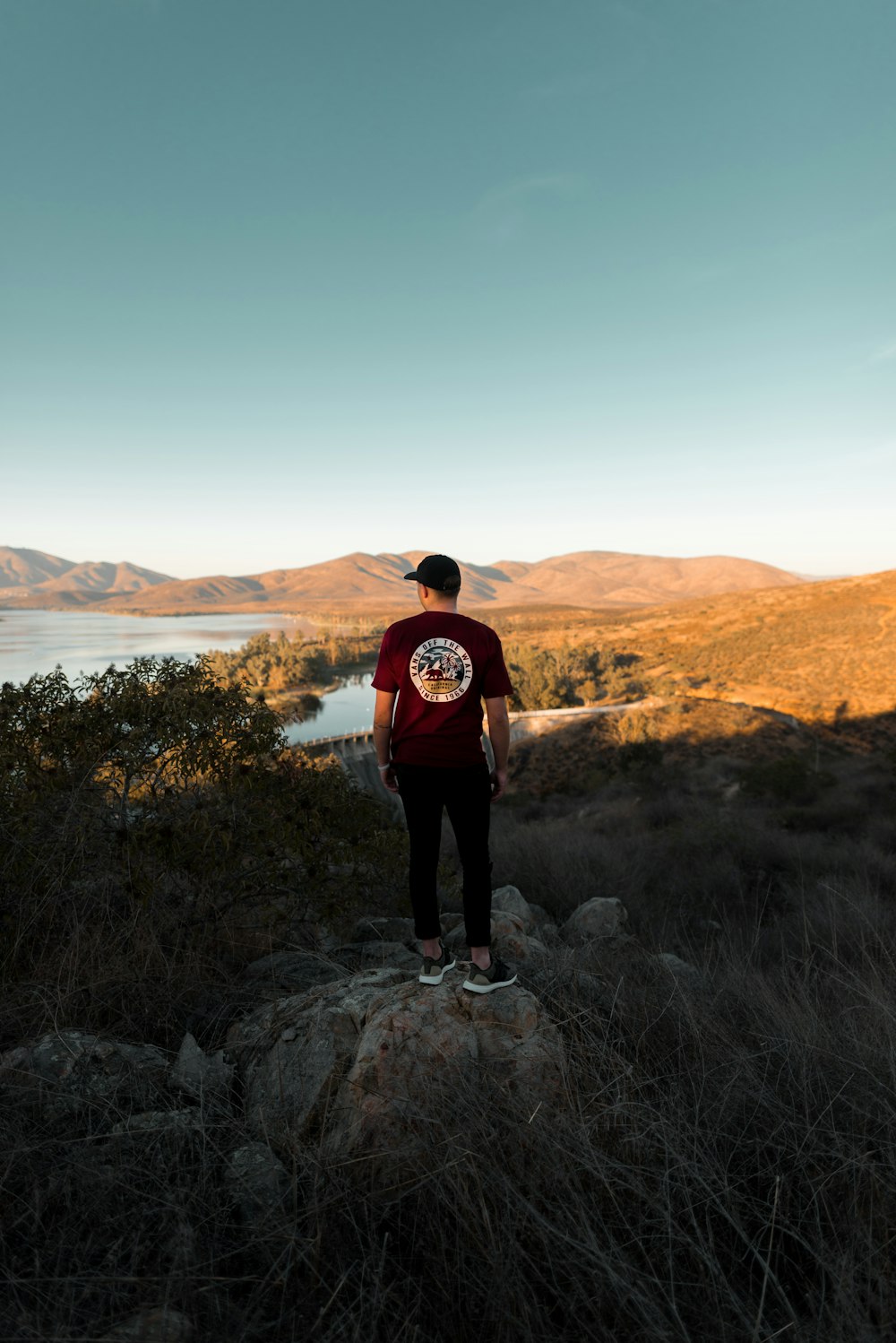 uomo in piedi sulla roccia mentre guarda i paesaggi