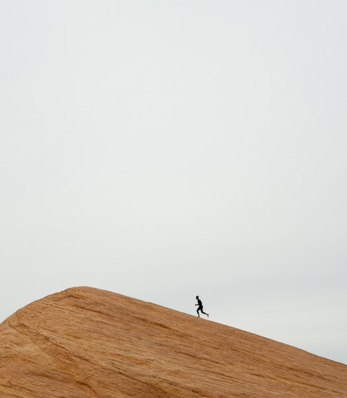 person running on top on hill during daytime