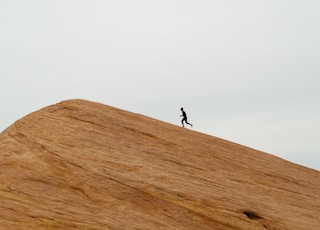 person running on top on hill during daytime