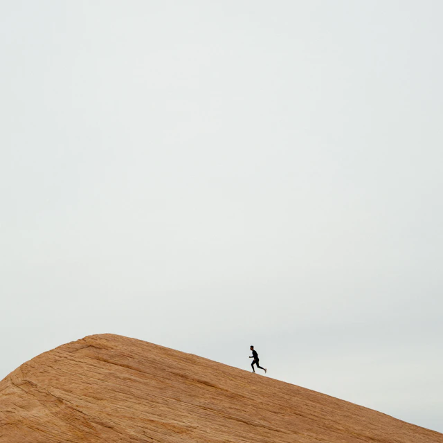 A person running along the top of a hill during the day