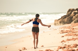 woman walking on sand near seashore during daytime