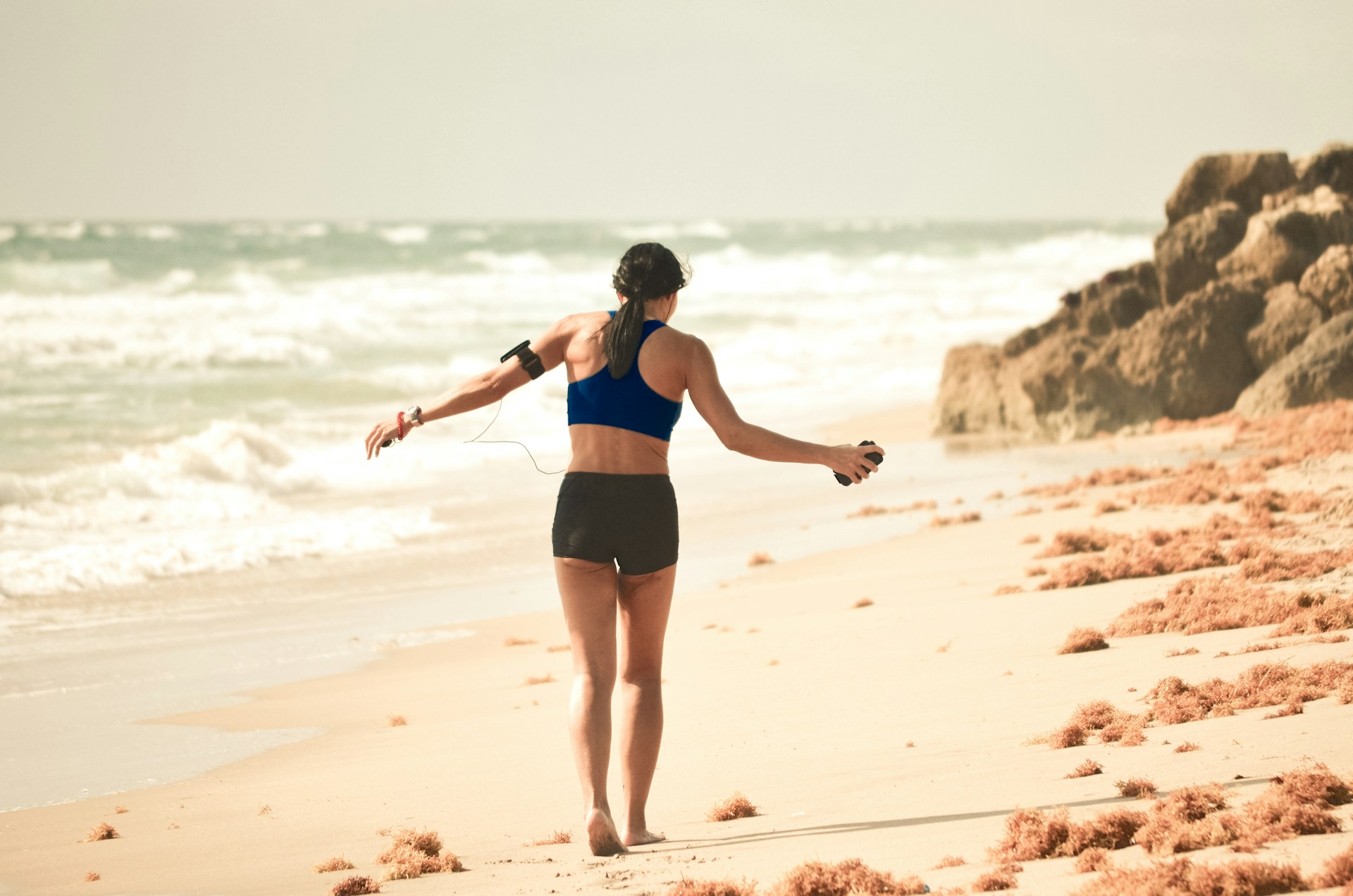 woman walking on sand near seashore during daytime