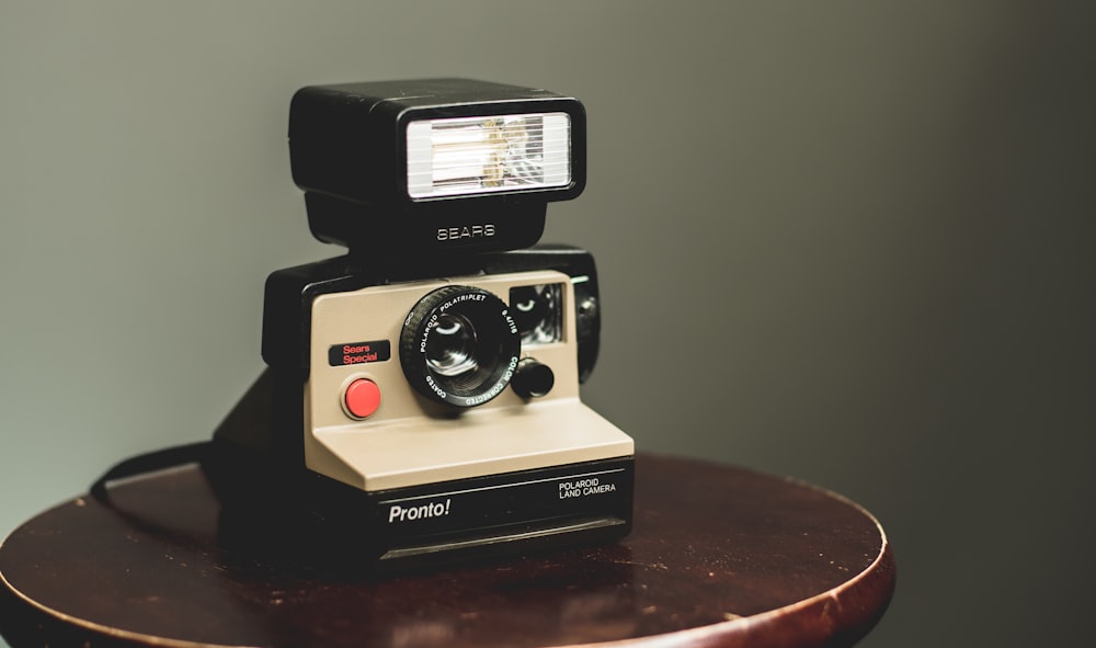 white and black camera on top of brown wooden table