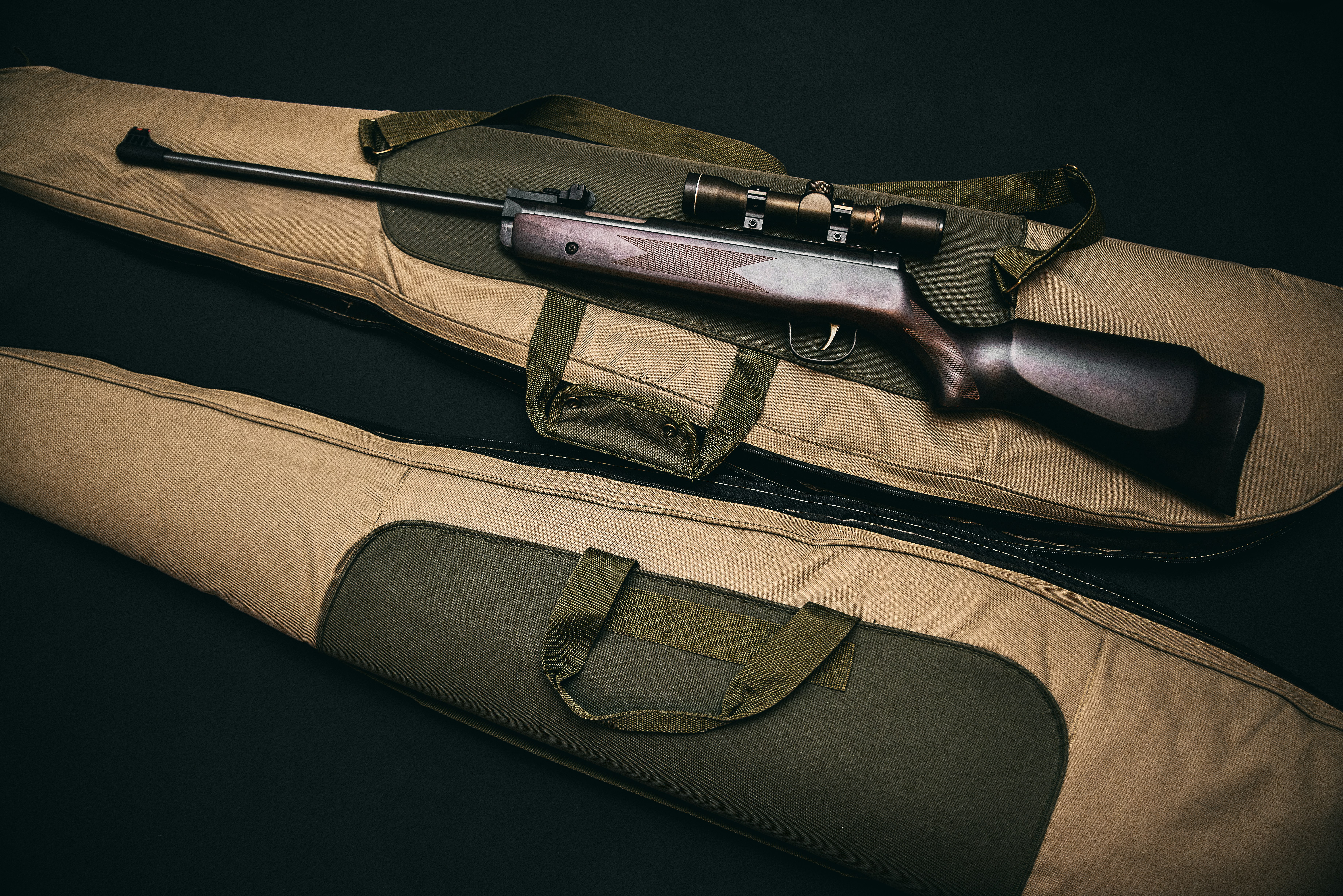 brown and black sniper rifle with beige bag