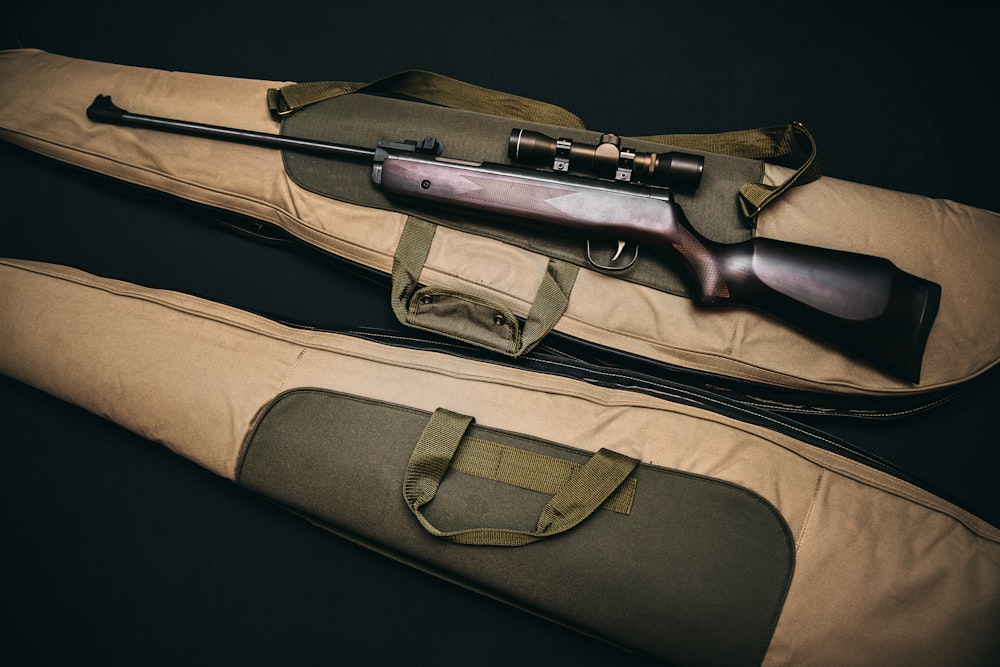 brown and black sniper rifle with beige bag