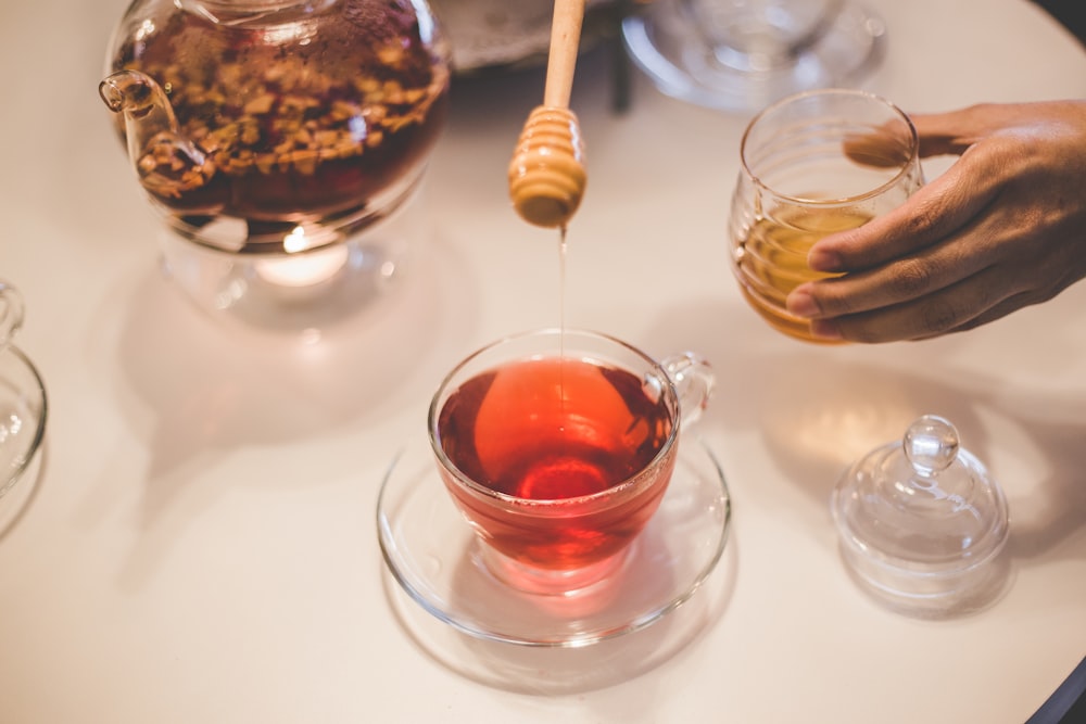 person putting honey on tea