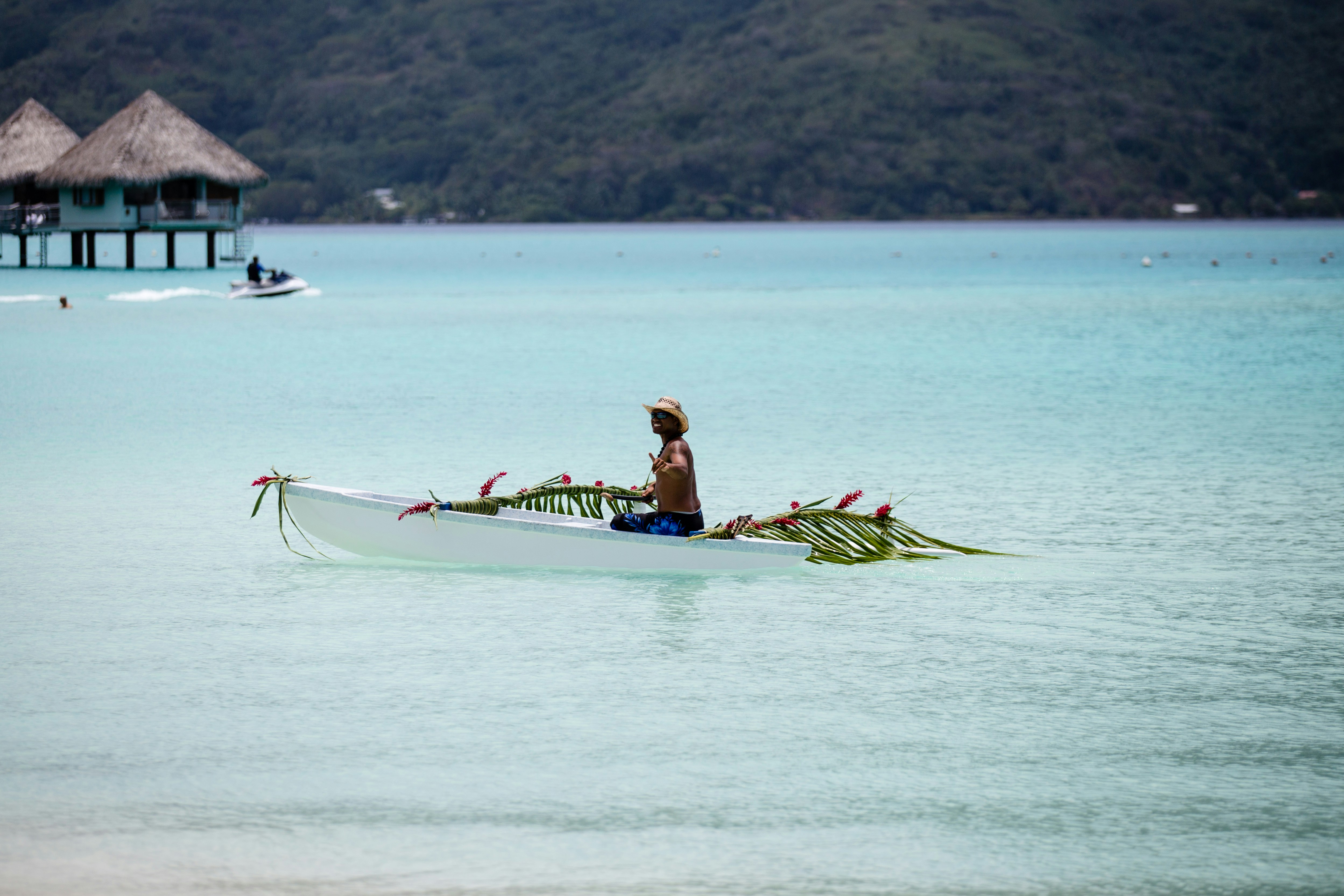 person riding on boat near hut, Happy Polynesian on the pirogue decorated for wedding. Island Bora Bora.