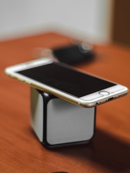 gold iPhone 6 on top of Bluetooth portable speaker