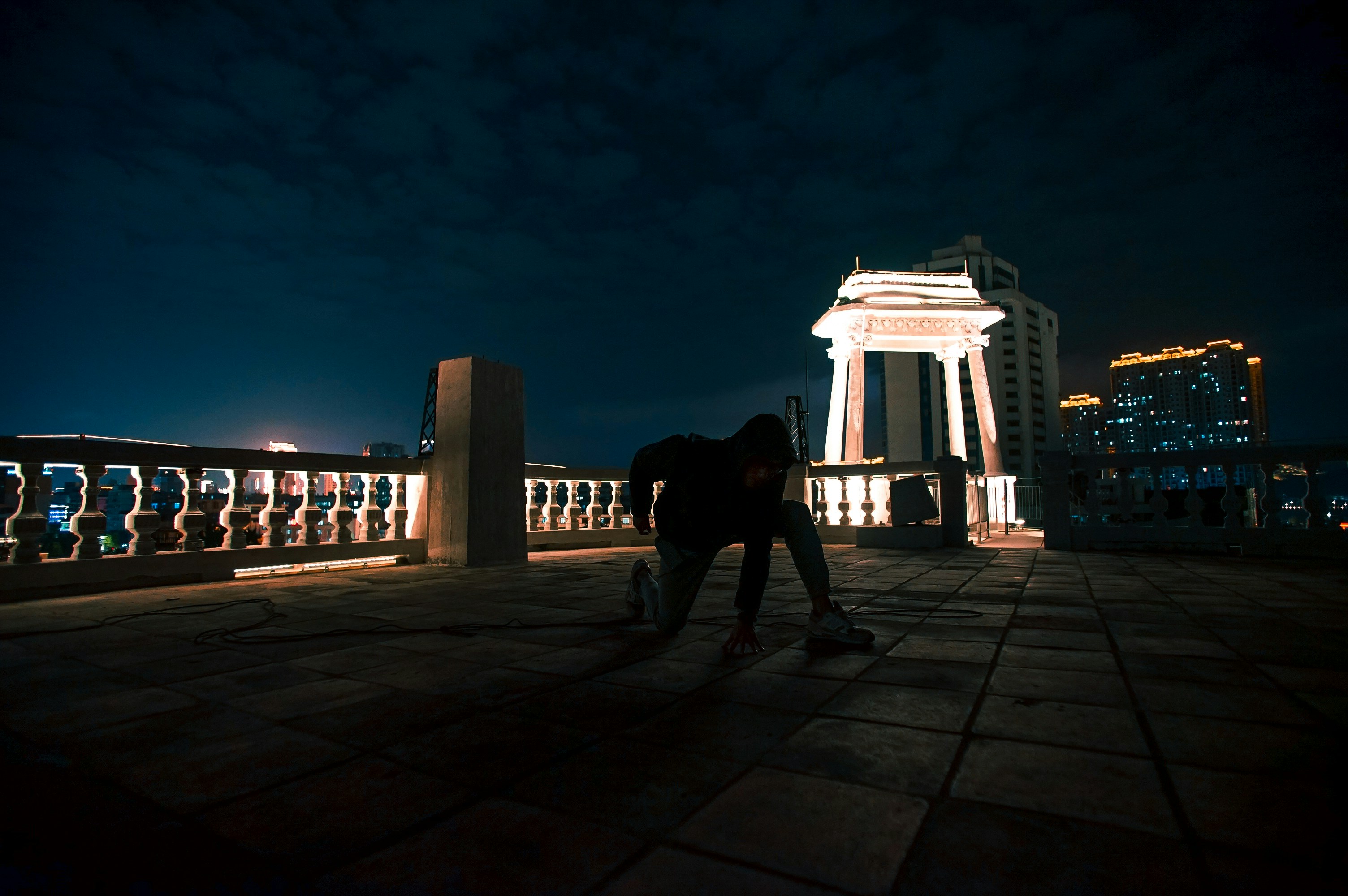 person in black outfit kneeling near concrete bench