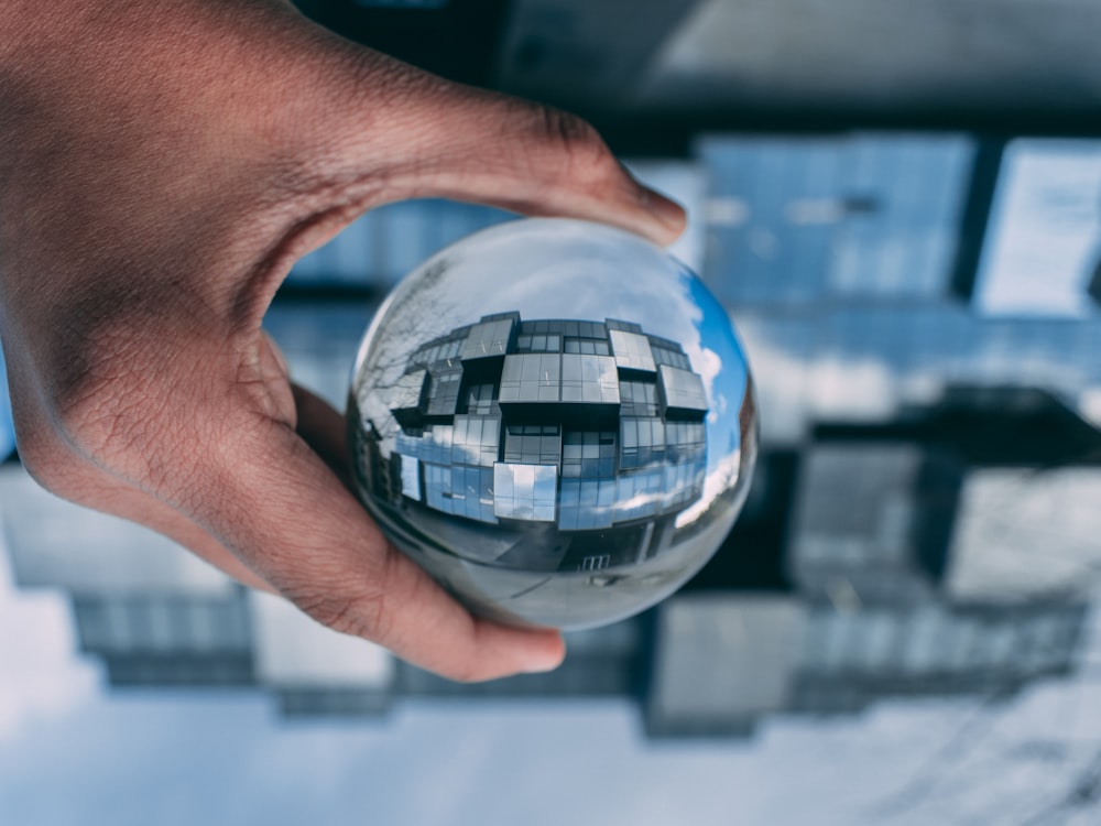 personne tenant une boule de verre transparent