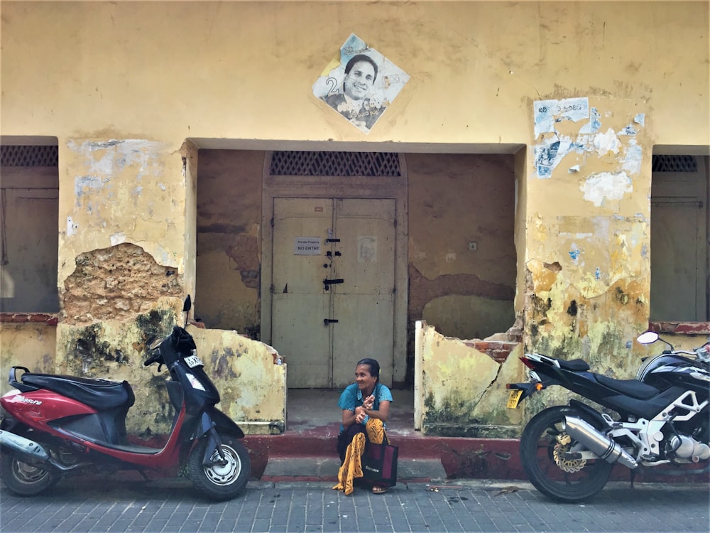 woman sitting between motorcycles