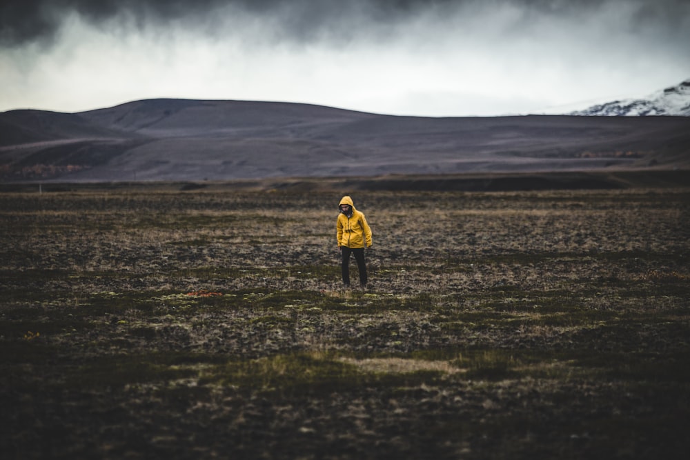 man standing on green grass field under gray sky