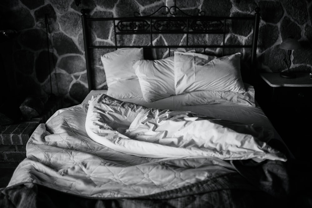 Una foto en blanco y negro de una cama sin hacer