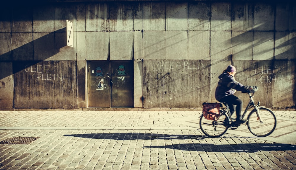 person riding bicycle near concrete wall
