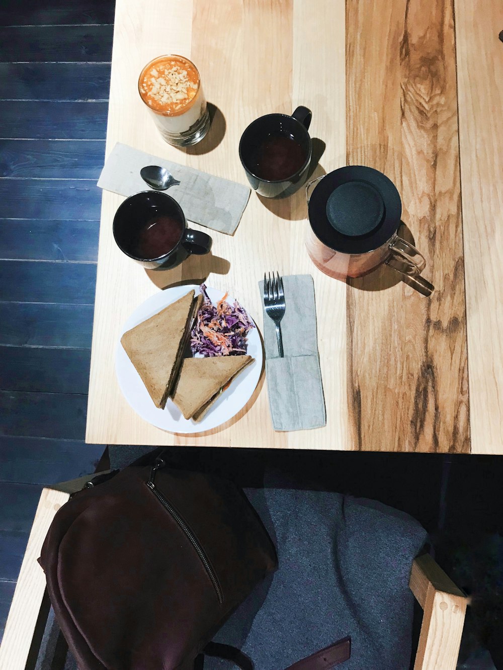 Mesa de madera con taza de café y plato de sándwich