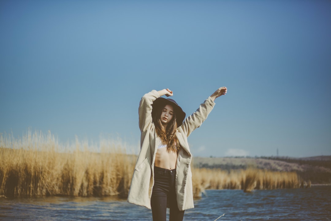 woman wearing coat near body of water