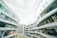 A modern library interior with curved, white bookshelves filled with a vast array of colorful books. The design creates a feeling of openness and spaciousness, accentuated by the softly lit ceiling. The floor is made of light wood, adding warmth to the environment.