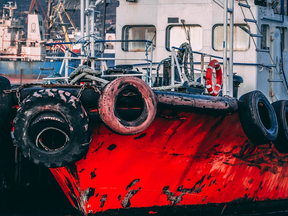 a large red boat sitting next to a white boat