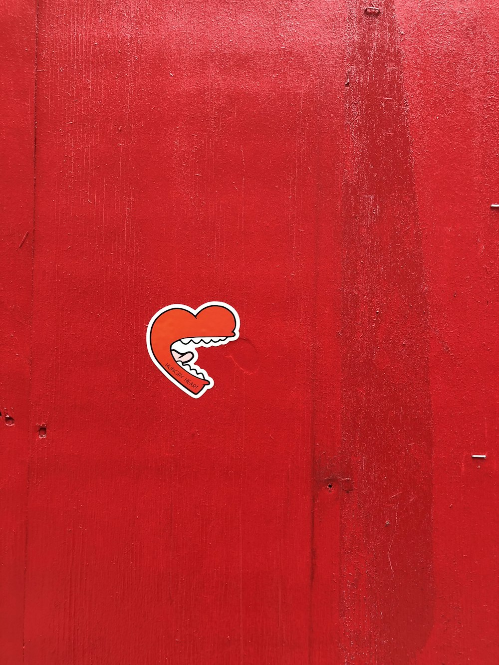 un muro rosso con un adesivo di un cuore su di esso