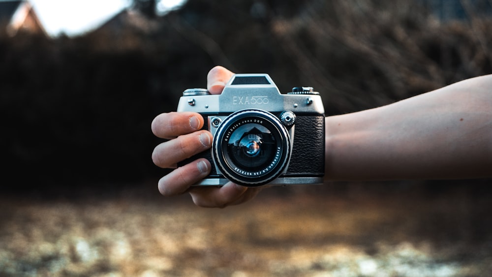 person holding gray camera in selective focus photography