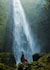 woman sitting on rock facing plunge waterfalls