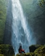 woman sitting on rock facing plunge waterfalls