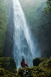 woman sitting on rock facing plunge waterfalls