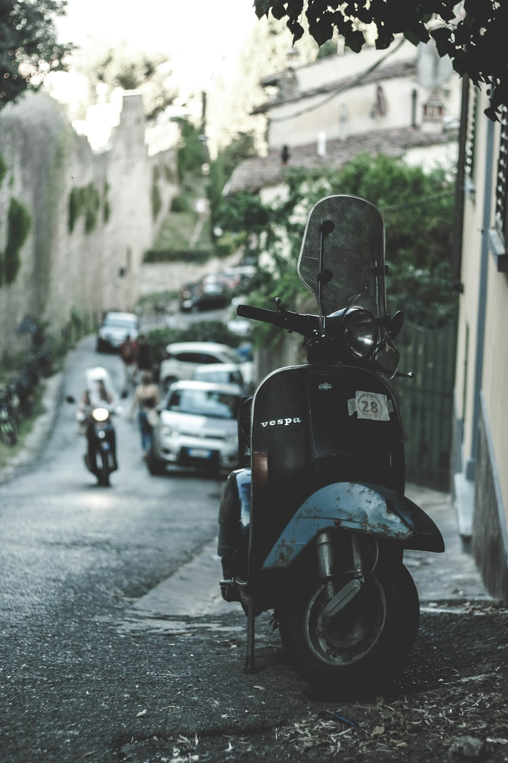 black Vespa motor scooter with windshield parked near the building