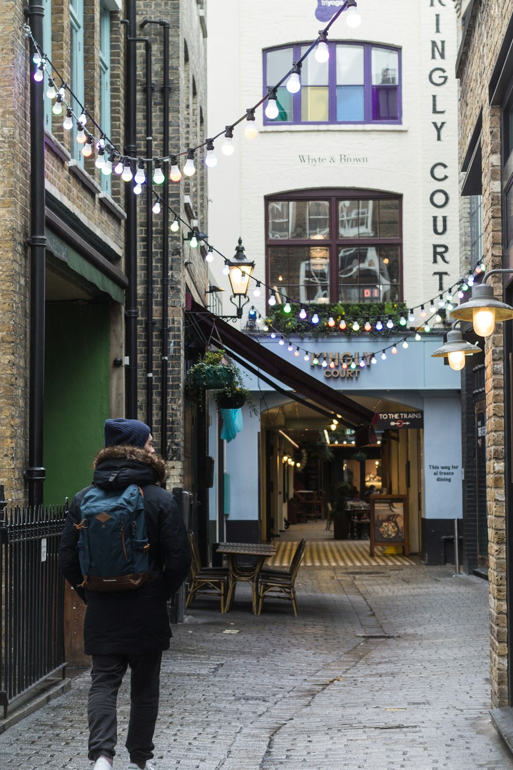 person wearing blue backpack while walking on narrow street