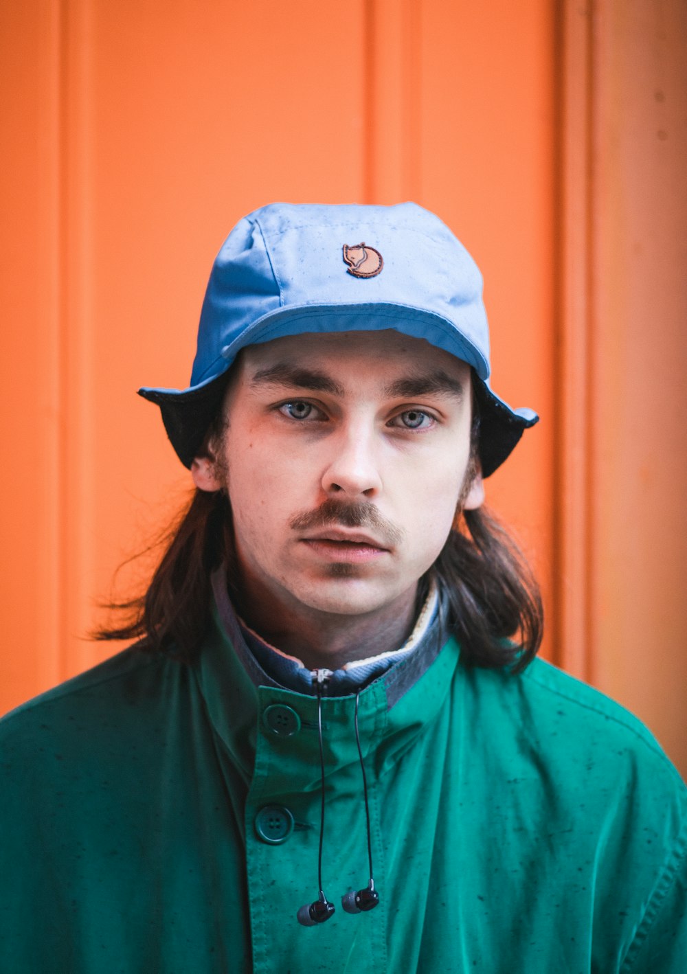 man wearing blue cap and green jacket looking straight to the camera