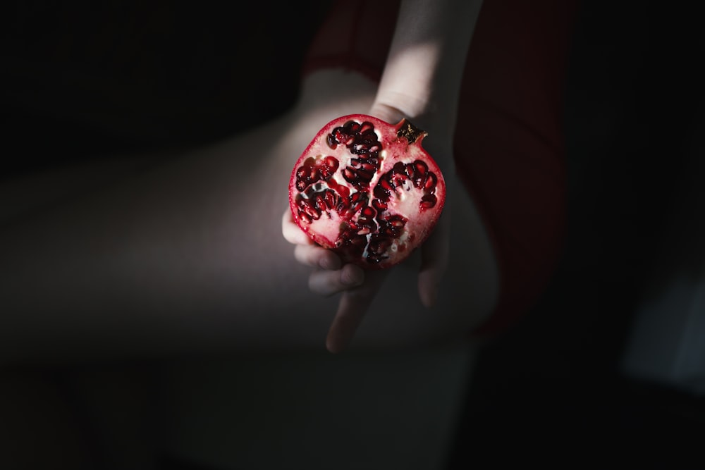 person holding red pomegranate