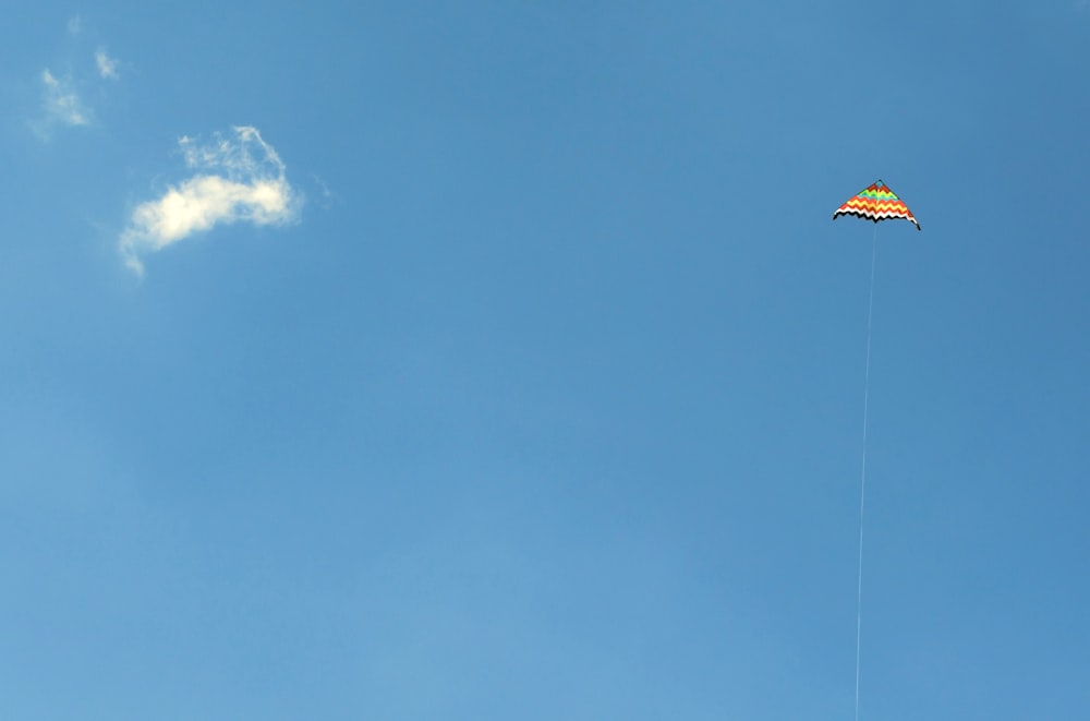 orange and green kite in the sky soaring at daytime