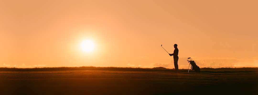 Silhouette of a golfer with low sun in the background