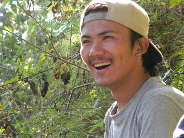 A close-up of a smiling guide pointing out local flora during an outdoor excursion.