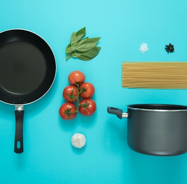 flat lay photography of frying pan beside tomatoes on blue surface