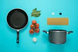 flat lay photography of frying pan beside tomatoes on blue surface