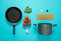 flat lay photography of frying pan beside tomatoes on blue surface