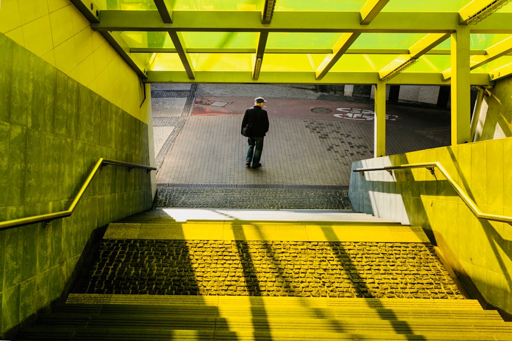 man standing on concrete path in front of stair during daytime