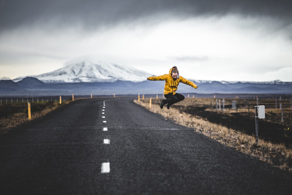 jump shot photo of man over road and mountain alps at distance