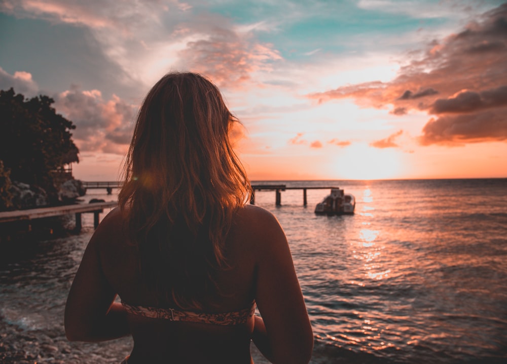 woman wearing bikini facing the sunset